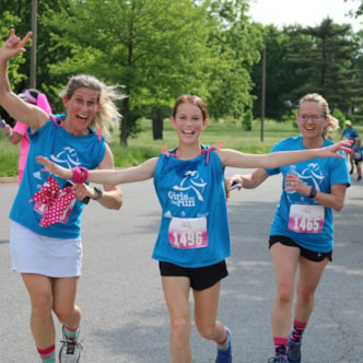 Two smiling Girls on the Run coaches running with participant at 5K 